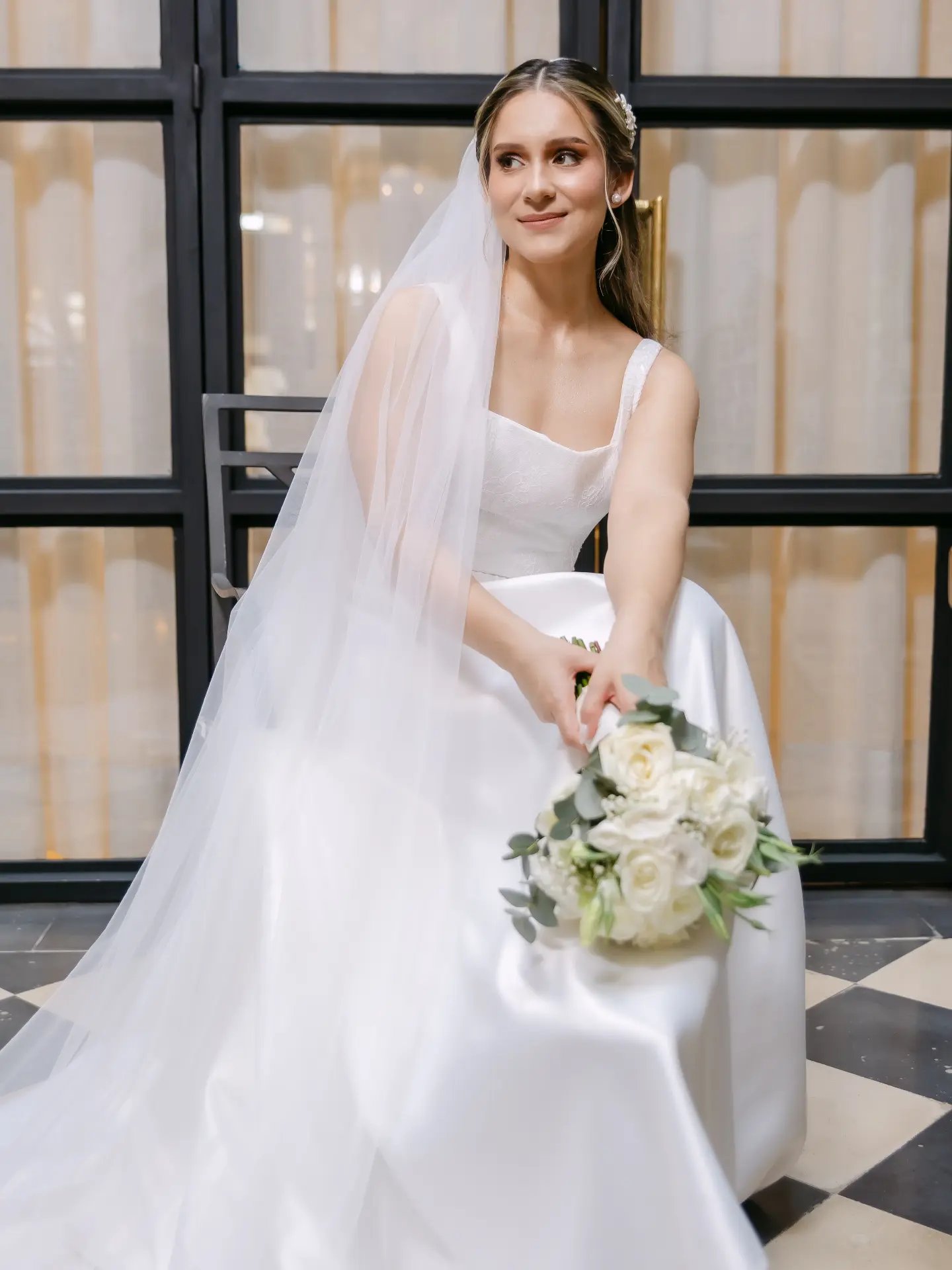 Novia sentada sonriendo con su ramo de novia, vestido Melisa Sebeca